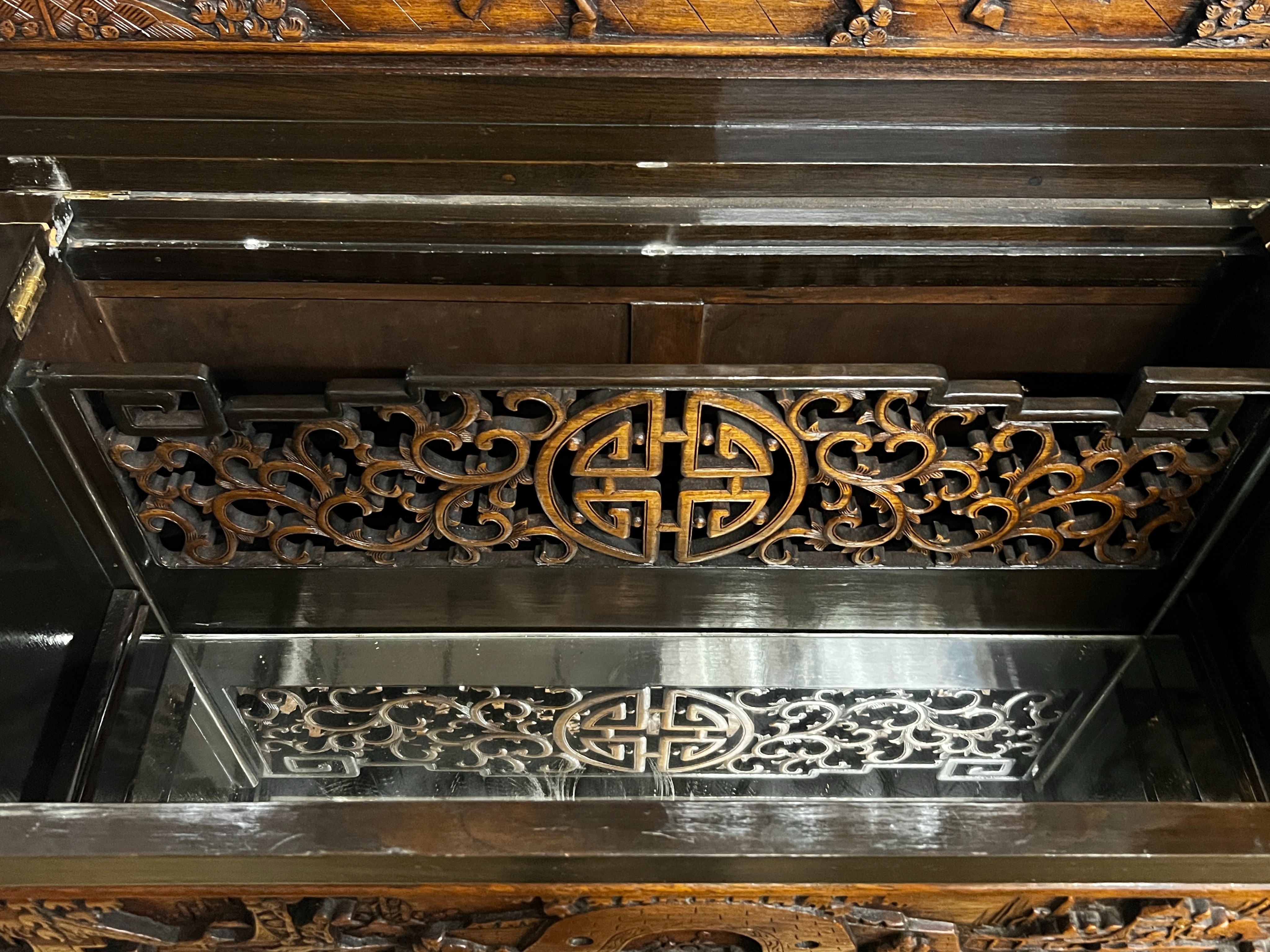 A Chinese carved hinged top cocktail cabinet with mirrored interior, width 111cm, depth 46cm, height 107cm